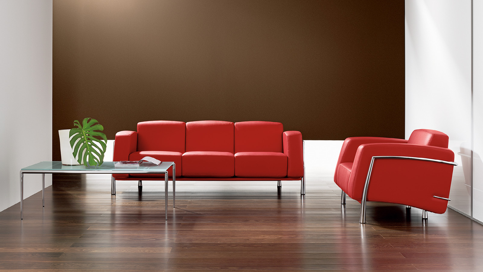 Przestrzeń do rozmów wyposażono w czerwoną, 3-osobową sofę, 1-osobowy fotel w tożsamym kolorze oraz szklany stolik kawowy.